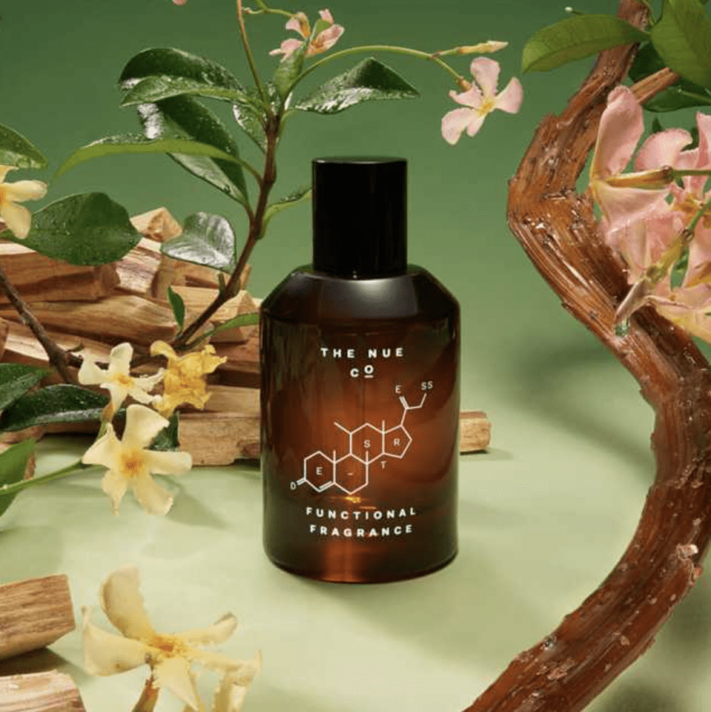 A bottle of cologne with flowers and branches on a green background, creating an enchanting and fresh ambiance.