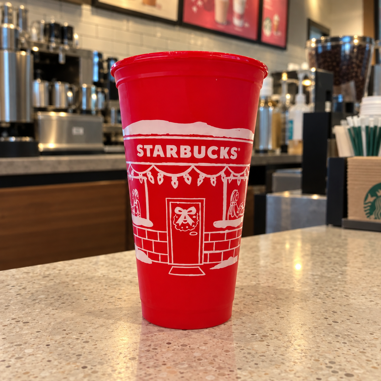 Previous-year Starbucks 2025 reusable red cup with a white coffeehouse illustration; not the announced 2026 design